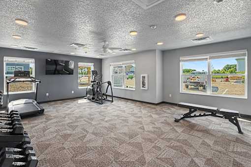 A spacious gym with a variety of equipment including treadmills, weights, and a bench.