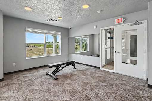 A room with a bench and a window overlooking a parking lot.