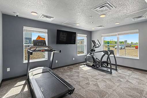 A spacious room with a treadmill, elliptical trainer, and a television.