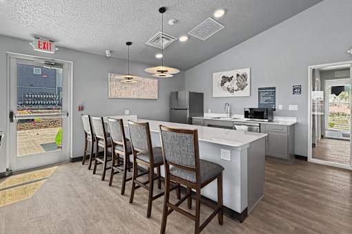 A kitchen with a white counter and brown chairs.