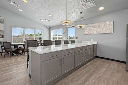 A kitchen with a large island and a dining table with chairs.