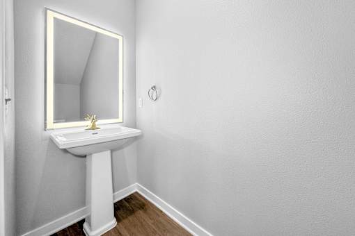 A white pedestal sink with a gold faucet and a mirror above it.