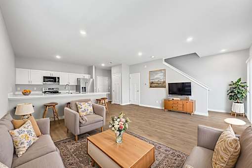 A living room with a grey couch, a brown coffee table, and a wooden staircase.