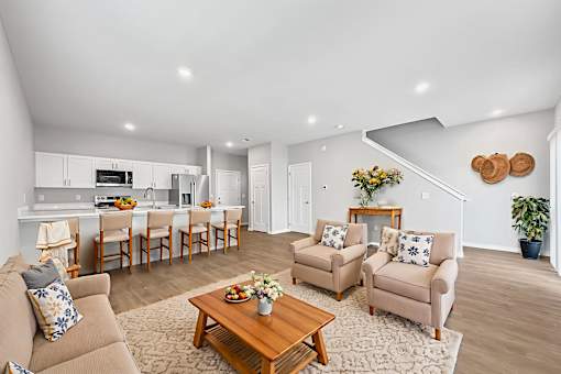 A living room with a brown couch, two chairs, and a coffee table.