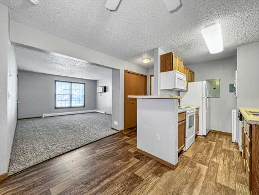 A kitchen with white appliances and wooden floors.