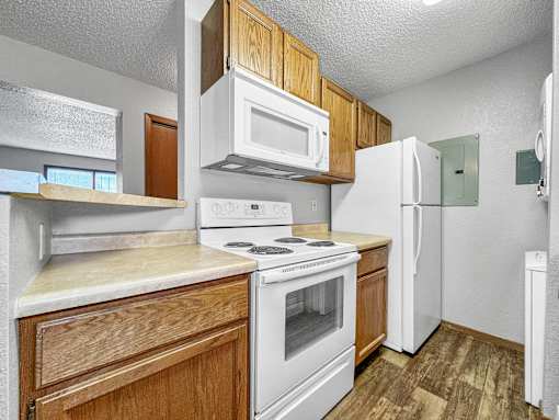 A kitchen with white appliances and wooden cabinets.