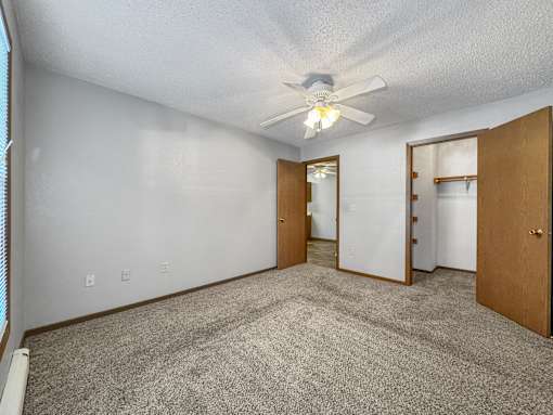 A room with a ceiling fan and carpeted floor.