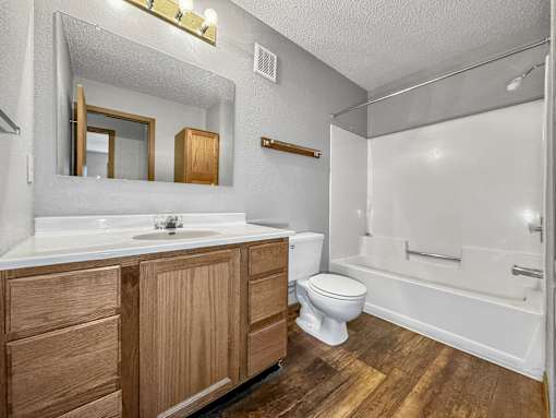 A bathroom with a white sink, wooden cabinets, and a white toilet.