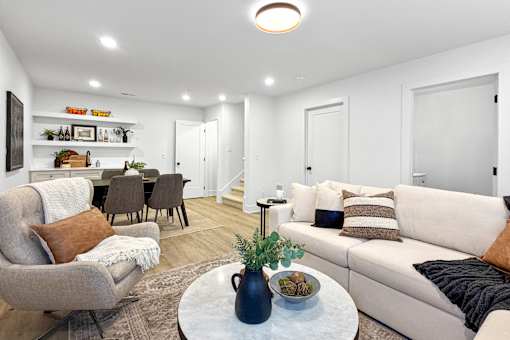 A spacious finished basement with sectional couch, wet bar, and sitting area.