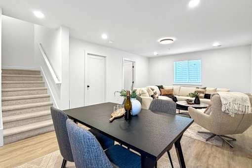 A spacious finished basement with a black table and blue chairs.
