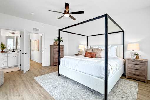 A primary bedroom with a four poster bed and a ceiling fan. Spacious floor plan with attached walk-in closet and on suite bathroom with double vanity.