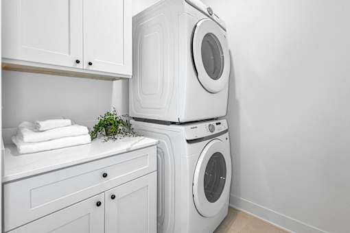 Private laundry room with white washing machine and dryer. With cabinet and counter space.