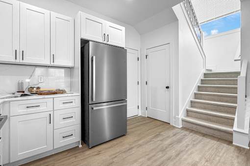A kitchen with white cabinets and a stainless steel refrigerator.