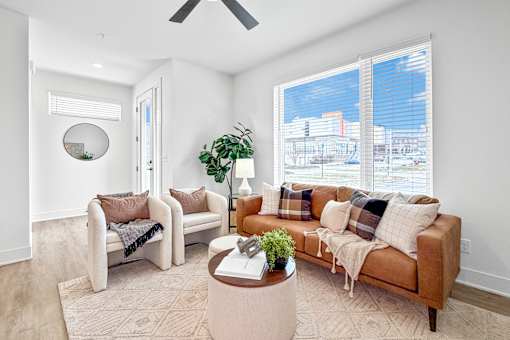 A living room with a couch, chair, and potted plant.