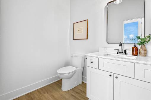 A white bathroom with a toilet, sink, and mirror.