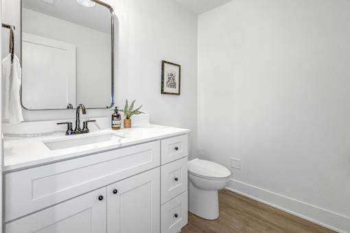 A white bathroom with a toilet, sink, and mirror.