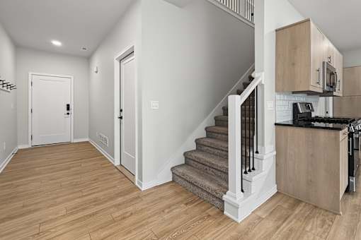 A white interior with a staircase and a kitchen area.
