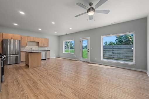 A spacious kitchen with wooden floors and a ceiling fan.