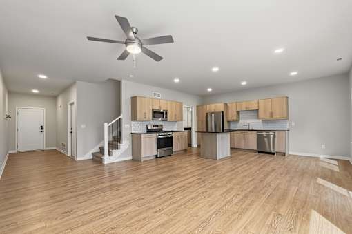 A spacious kitchen and living room with wooden floors and modern appliances.