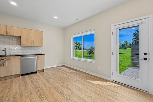 A kitchen with wooden floors and a window showing a green lawn outside.