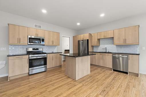 A kitchen with wooden cabinets and a black refrigerator.