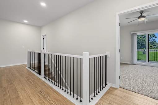 A room with a white railing and wooden flooring.
