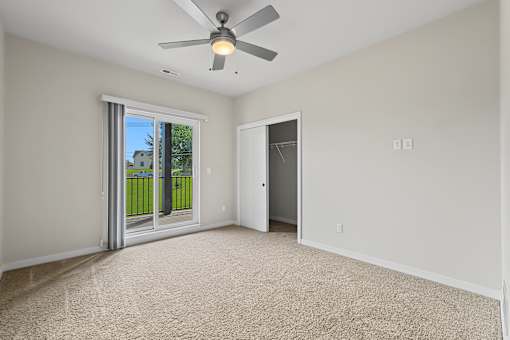 A room with a ceiling fan and carpeted floor.