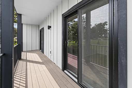 A long balcony with a black railing and a glass door.