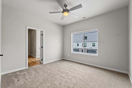 A room with a ceiling fan and a window with blinds.