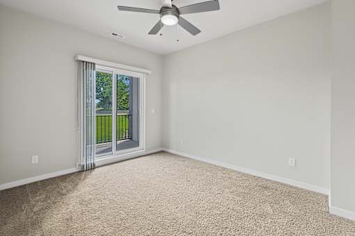 A room with a ceiling fan and carpeted floor.