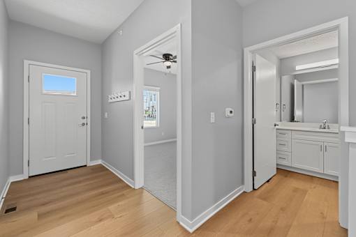 A room with a door, a mirror, and a ceiling fan.