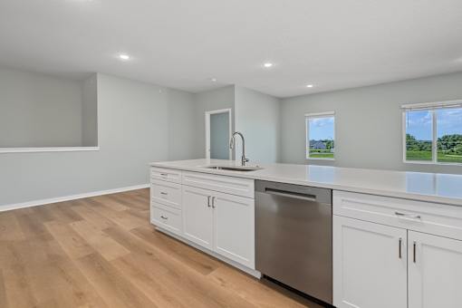 A kitchen with white cabinets and a wooden floor.