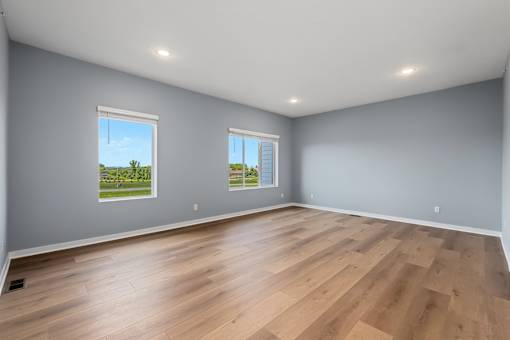 A room with wooden floors and two windows.