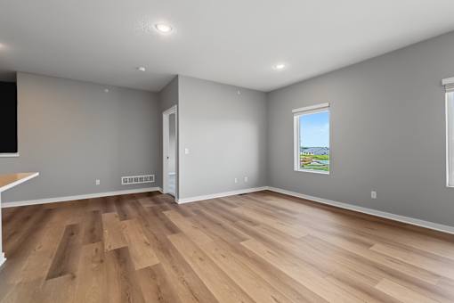 A room with wooden flooring and a window showing a green landscape.