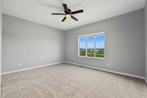 A room with a ceiling fan and a window showing a view of the outdoors.