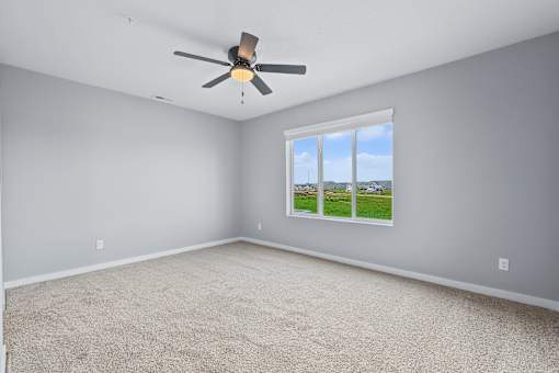 A room with a ceiling fan and a window showing a view of the outdoors.