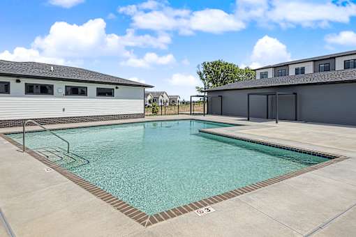 A swimming pool with a metal ladder and a building in the background.
