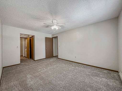an empty living room with white walls and a ceiling fan at Creekstone Falls, Sioux Falls, 57106