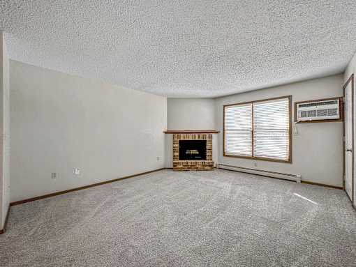 an empty living room with a fireplace and a window at Creekstone Falls, Sioux Falls