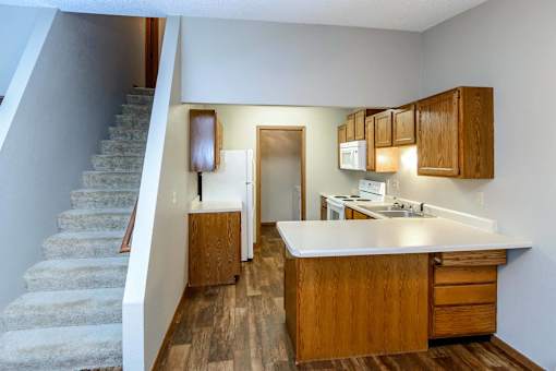 a kitchen with a sink and a refrigerator next to stairs at Creekstone Falls, Sioux Falls, SD, 57106