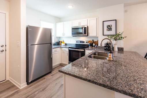 a kitchen with granite counter tops and a stainless steel refrigerator at Forge65, Pleasant Hill, Iowa