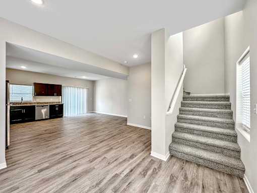 a renovated living room with a staircase and a kitchen at Forge65, Pleasant Hill, 50327