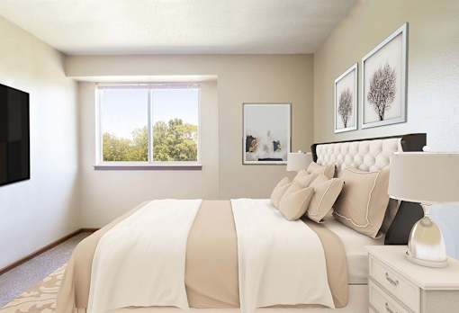 A bedroom with a large bed and a window showing trees outside at Hunters Run Apartments, Newton, Iowa
