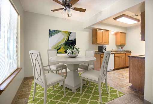 A dining room with a white table and chairs at Hunters Run Apartments, Newton, IA