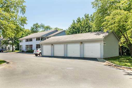 A white car is parked in front of a two-story house with a garage at Hunters Run Apartments, Newton, IA,  50208