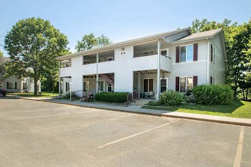 A white two-story building with a parking lot in front at Hunters Run Apartments, Newton
