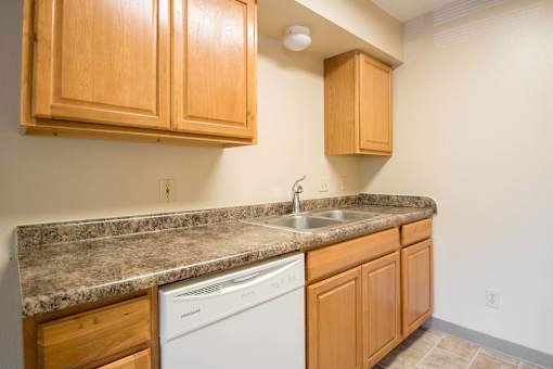 A kitchen with wooden cabinets and a granite countertop at Hunters Run Apartments, Newton, IA