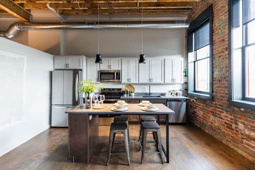 A kitchen with a table and chairs in the middle of the room.at Plant 1 Lofts, N. Newton, IA  