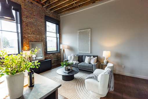 A living room with a grey couch and a white chair.at Plant 1 Lofts, N. Newton, 50208  