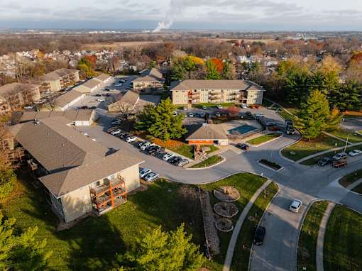 An aerial view of a parking lot and buildings with trees in the background at Rosemont Place Apartments, Iowa, 50320